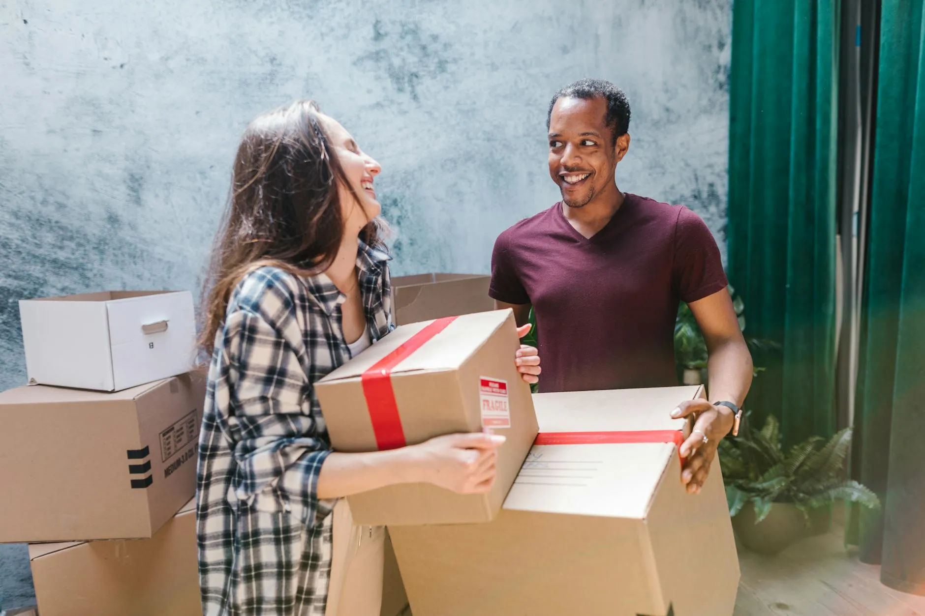 Young couple carrying moving boxes into their first home