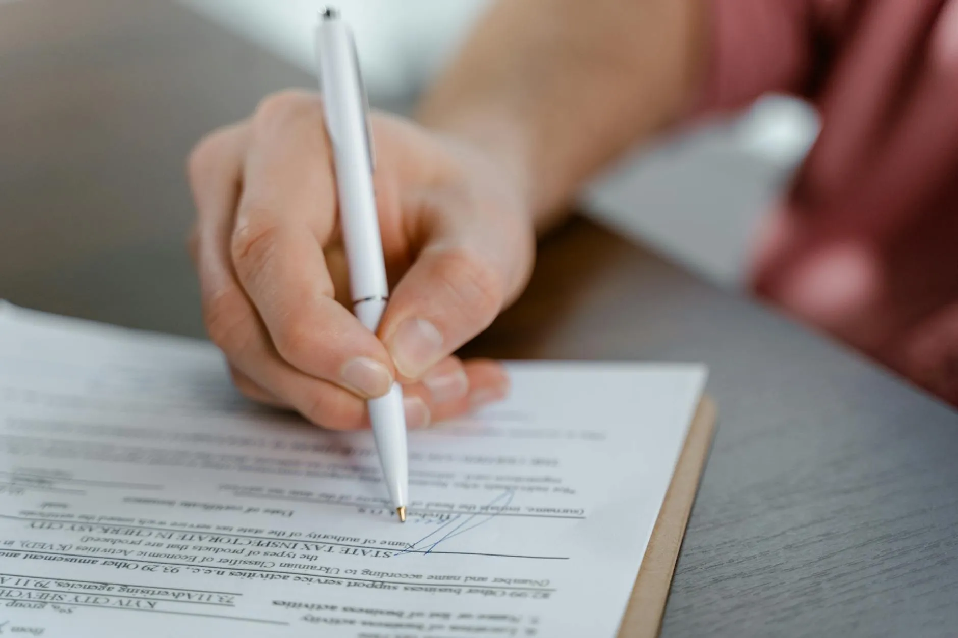 Hand signing closing documents on a desk